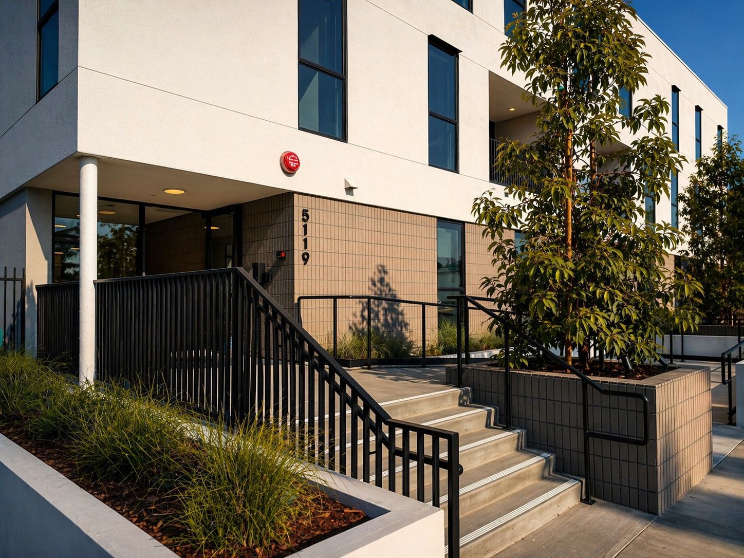 The entrance of 5119 Colfax: a white contemporary mid-rise with landscaped stairs