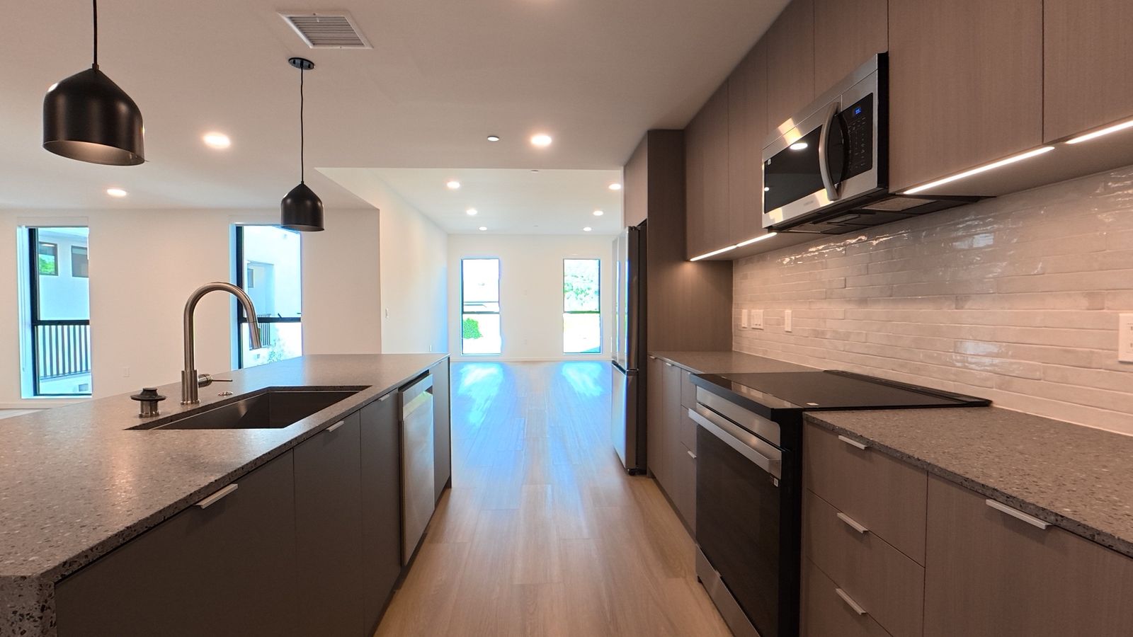 Kitchen with waterfall island, pendant lights and stainless appliances